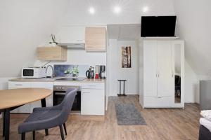 ギュンツブルクにあるFerienwohnung Erhardtの小さなキッチン(白いキャビネット、テーブル、椅子付) +14枚の写真