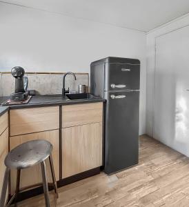a kitchen with a refrigerator and a sink and a stool at Le coin cosy d'Anglet in Anglet