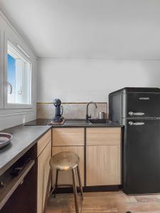 a kitchen with a black refrigerator and a stool at Le coin cosy d'Anglet in Anglet