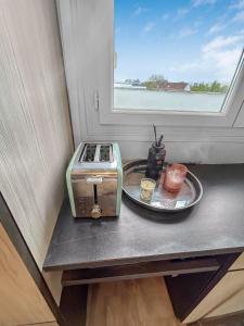 a toaster and a plate on a counter with a window at Le coin cosy d'Anglet in Anglet