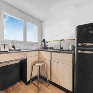 uma cozinha com um frigorífico preto e um banco em Le coin cosy d'Anglet em Anglet