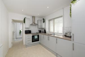 Una cocina blanca con gabinetes blancos y un fregadero. en Modern House near Washeries Park, en Nant-y-moel