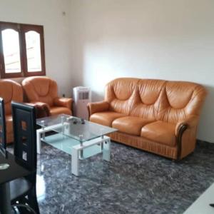 a living room with a leather couch and a table at Résidences la Diaspora in Yaoundé +2 photos