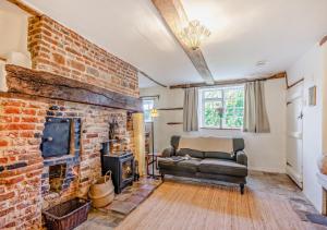 a living room with a brick fireplace and a couch at Bakers Cottage - Sidestrand in Sidestrand