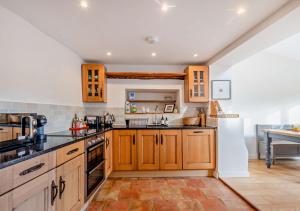 a large kitchen with wooden cabinets and appliances at Bakers Cottage - Sidestrand in Sidestrand