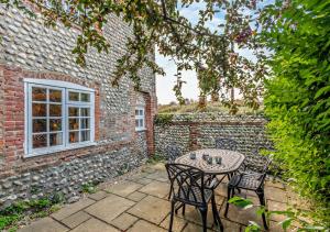 a patio with a table and chairs in front of a brick building at Bakers Cottage - Sidestrand in Sidestrand