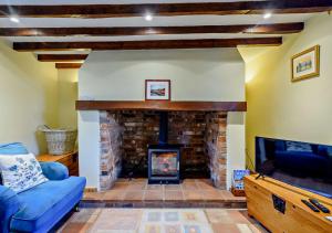 Panxworth的住宿－Holly Cottage，客厅设有壁炉和电视。