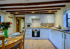 Panxworth的住宿－Holly Cottage，厨房配有白色橱柜和木桌