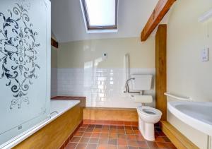 a bathroom with a toilet and a tub and a sink at Pond Cottage in Sidestrand