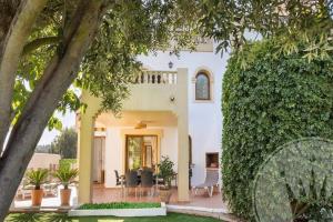 a white house with a porch and chairs and trees at La Manga Club - Monte Claro 606 in Atamaría