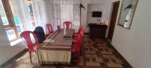 a dining room with a table and red chairs at Jahangir Cottage Pahalgam in Pahalgām