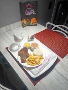 um prato de carne e batatas fritas e um copo de vinho em Prestige Motel 1 em São Paulo
