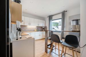 a kitchen with white cabinets and black chairs in it at Eifel-resort in Waxweiler