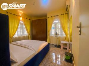 a bedroom with a bed with yellow curtains and a cross at IMSMART Luxury Homes in Uyo