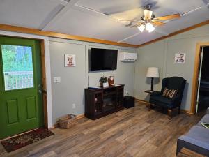 a living room with a green door and a television at Frog Hollow at Hocking Vacations in Logan