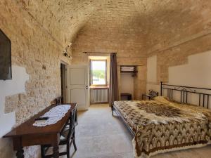 a bedroom with a bed and a table and a window at Masseria Santolomuto in Noci