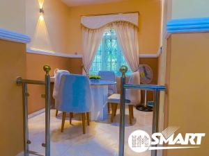 a dining room with a table and chairs and a window at IMSMART Luxury Homes in Uyo