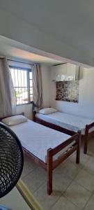 a bedroom with two beds and a chair at Pousada Mar Dos Anjos in Arraial do Cabo