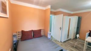 Schlafzimmer mit orangefarbenen Wänden und einem Bett mit Kissen in der Unterkunft Bonrila Sun Apartman in Zamárdi