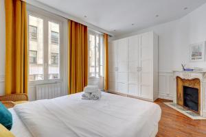 1 dormitorio con cama blanca y chimenea en 101- Beautiful apartment near champs elysees en París