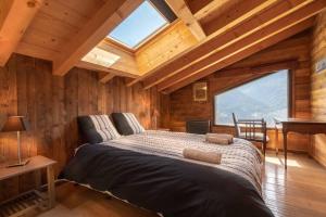 een slaapkamer met een bed in een houten hut bij Chalet Apalosa - Montvalezan, La Rosière in Montvalezan