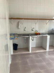 a kitchen with a sink and a tiled wall at Jasmim Manga pousada e Cafe in Ubatuba