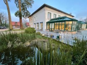 een gebouw met een vijver ervoor bij Logis - Hotel Restaurant La Sapinière in Wisques