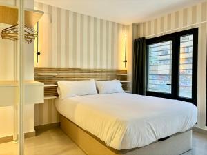 Un dormitorio con una gran cama blanca y una ventana en Gulliver Suites Valencia, en Valencia