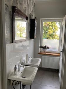 a bathroom with two sinks and two windows at Villa Italiana pokoje z prywatnymi łazienkami & Odnowa Biologiczna in Gdynia