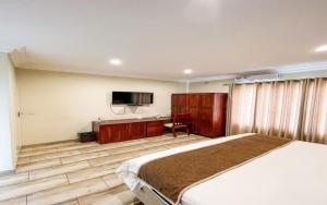 een slaapkamer met een bed, een bureau en een televisie bij Pemabwe Guest Lodge in Harare