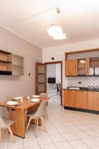kuchnia i jadalnia z drewnianym stołem i krzesłami w obiekcie Spacious Exclusive Apartment w mieście Pioltello