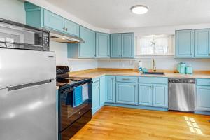 a kitchen with blue cabinets and a white refrigerator at Calm Seas Cottage in Falmouth