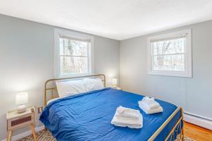a bedroom with a blue bed with towels on it at Calm Seas Cottage in Falmouth
