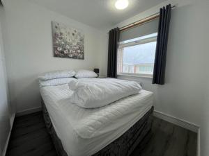 a bedroom with a bed with white sheets and a window at Chalet 319, Hemsby - Two bed chalet, sleeps 5, pet friendly, bed linen and towels included in Hemsby