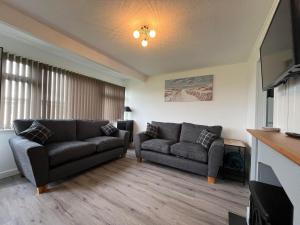 a living room with two couches and a flat screen tv at Chalet 319, Hemsby - Two bed chalet, sleeps 5, pet friendly, bed linen and towels included in Hemsby