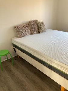 ein kleines Bett in einem Zimmer mit einem grünen Stuhl in der Unterkunft Poppel alle 2 b Hirtshals in Hirtshals