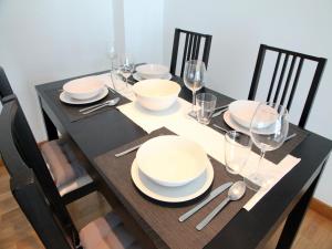 una mesa negra con platos blancos y gafas. en Precioso apartamento en Santoña, en Santoña