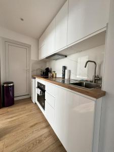 una cocina con armarios blancos y fregadero en Joli appartement dans une maison remise à neuf, en Mittelhausbergen