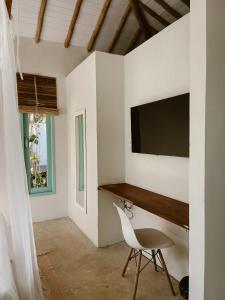 Zimmer mit einem Schreibtisch und einem TV an der Wand in der Unterkunft Pousada Refazenda in Corumbau