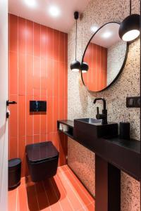 パリにあるCentral Apartment - Shopping at your Doorstepのオレンジ色のバスルーム(黒い洗面台、鏡付)