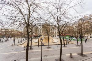 einen Park mit Bäumen und einem Brunnen in einer Stadt in der Unterkunft Central Apartment - Shopping at your Doorstep in Paris