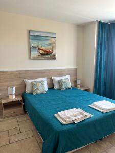 ein Schlafzimmer mit einem Bett mit blauer Bettwäsche und einem Gemälde in der Unterkunft Sea stars Kaliakria resort in Topola