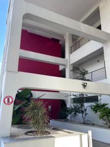 un bâtiment blanc avec un mur rouge dans l'établissement Alex Residence, à Larnaka