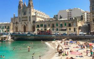 a group of people on a beach in front of a building at Sliema Jacuzzi Flat in Sliema