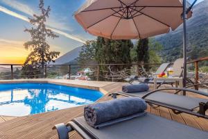 a patio with a pool and an umbrella and chairs at Traditional House with Private Pool in Rethymno