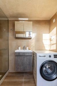 a bathroom with a washing machine and a sink at Traditional House with Private Pool in Rethymno