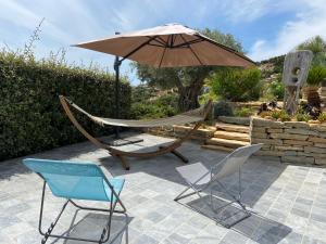 un patio con amaca e sedie sotto un ombrellone di Appartement privé à la Villa Paradis de Valcros a La Londe-les-Maures