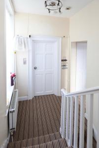 a hallway with a white door and a staircase at LORD MERIT GUEST HOUSE KING'S CROSS GRAYS INN ROAD in London