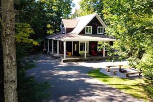 a house with a picnic bench in front of it at The Hidden Porch at Sir Sam's (hot tub & sauna) in Haliburton