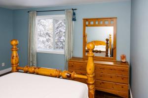 a bedroom with a bed and a mirror and a dresser at The Hidden Porch at Sir Sam's (hot tub & sauna) in Haliburton